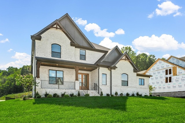 exterior space featuring covered porch, a yard, french doors, and brick siding