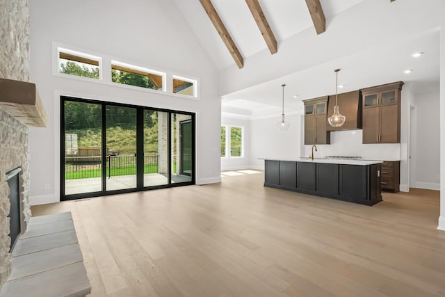 unfurnished living room featuring baseboards, high vaulted ceiling, light wood-style floors, and a sink