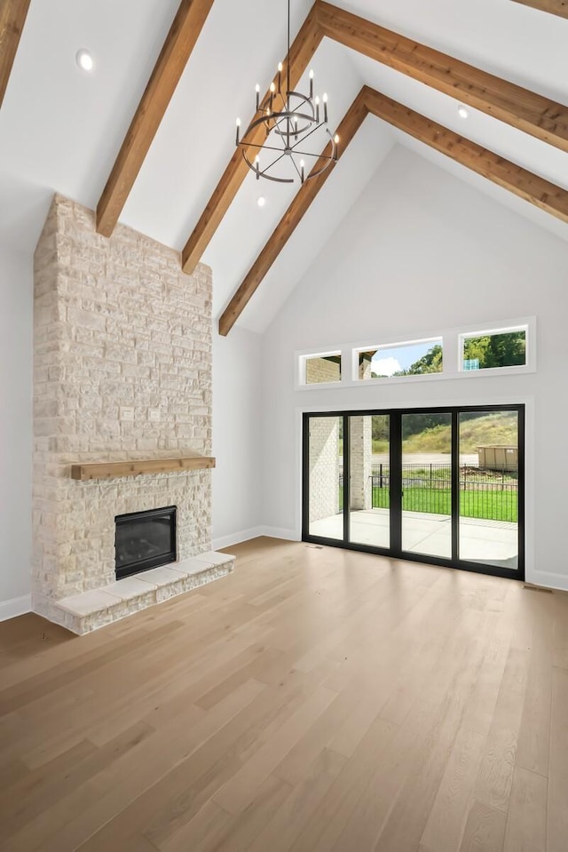 unfurnished living room featuring beamed ceiling, a fireplace, a notable chandelier, high vaulted ceiling, and baseboards