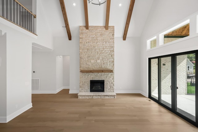 unfurnished living room featuring high vaulted ceiling, beam ceiling, wood finished floors, and visible vents