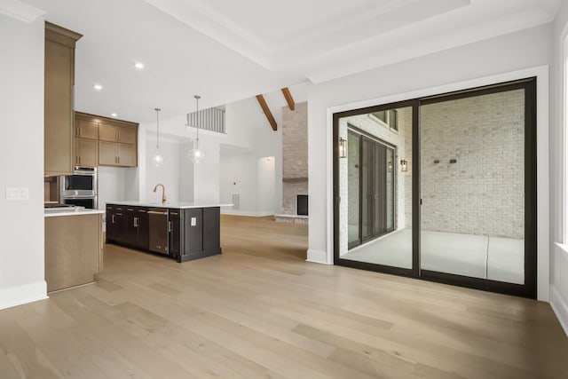 kitchen with stainless steel appliances, light wood-style floors, light countertops, a sink, and open floor plan