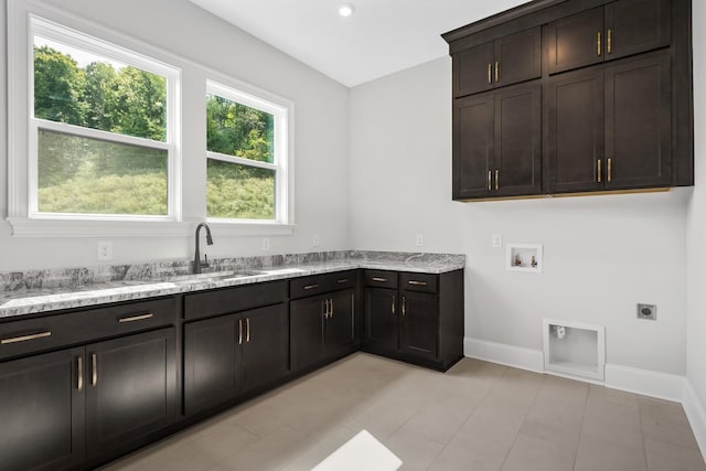 clothes washing area featuring hookup for an electric dryer, a sink, cabinet space, hookup for a washing machine, and baseboards