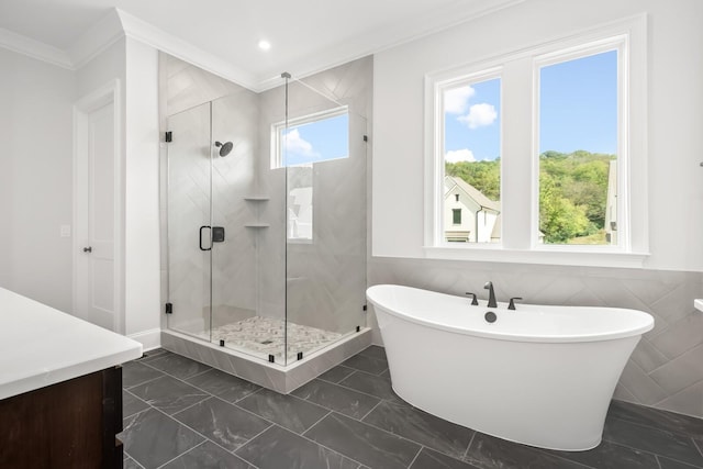 full bathroom featuring a soaking tub, a stall shower, ornamental molding, tile walls, and marble finish floor