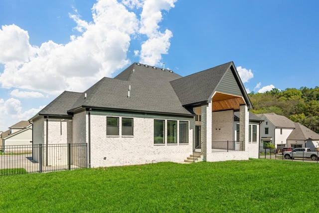 back of property featuring fence, a yard, and roof with shingles
