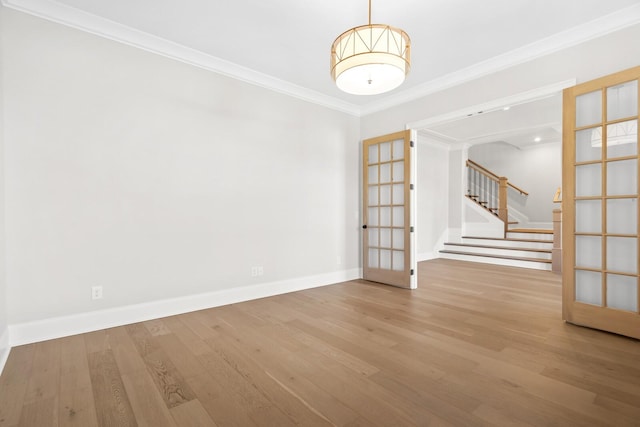 spare room featuring stairway, wood finished floors, french doors, and crown molding