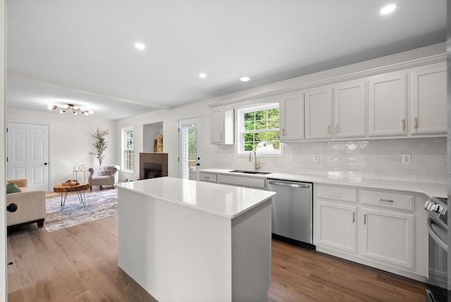 kitchen featuring stove, a kitchen island, dishwasher, a fireplace, and a sink