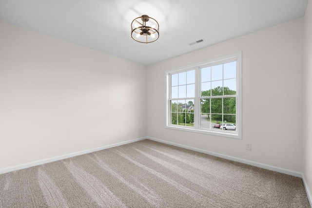 spare room with baseboards, visible vents, a notable chandelier, and carpet floors