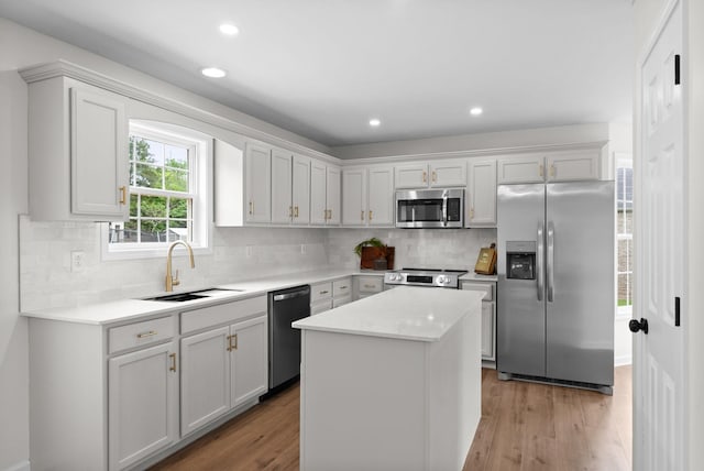 kitchen featuring a sink, stainless steel appliances, light wood-style floors, tasteful backsplash, and light countertops