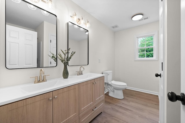 bathroom with toilet, a sink, and visible vents