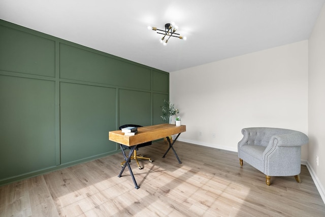 office with a decorative wall, baseboards, a notable chandelier, and light wood-style floors