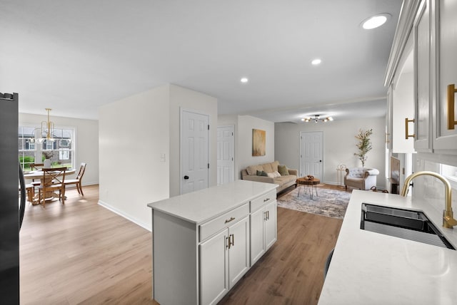 kitchen featuring light countertops, a sink, a chandelier, and baseboards
