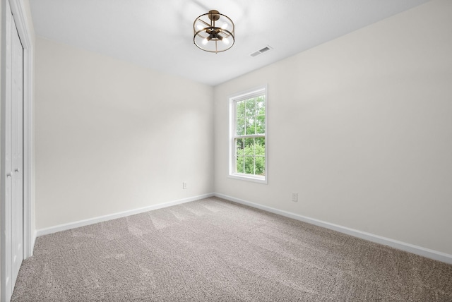 unfurnished room featuring carpet flooring, a notable chandelier, visible vents, and baseboards