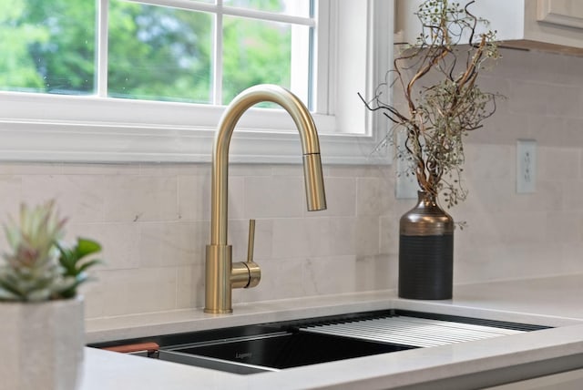room details with light countertops, decorative backsplash, and a sink
