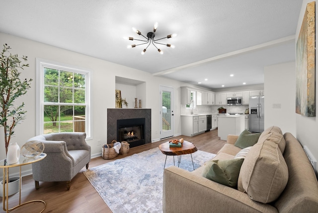 living area with a fireplace, a notable chandelier, light wood-style floors, and plenty of natural light
