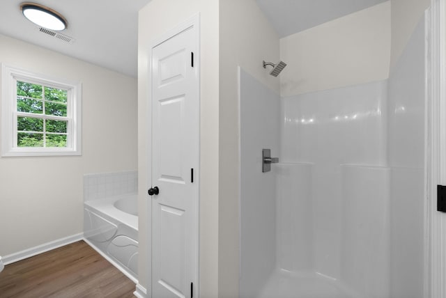 bathroom featuring visible vents, a shower, baseboards, a garden tub, and wood finished floors