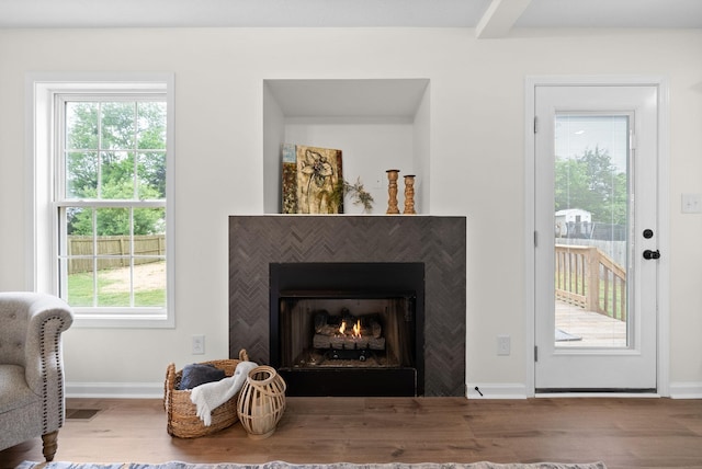 details with visible vents, wood finished floors, a lit fireplace, and baseboards