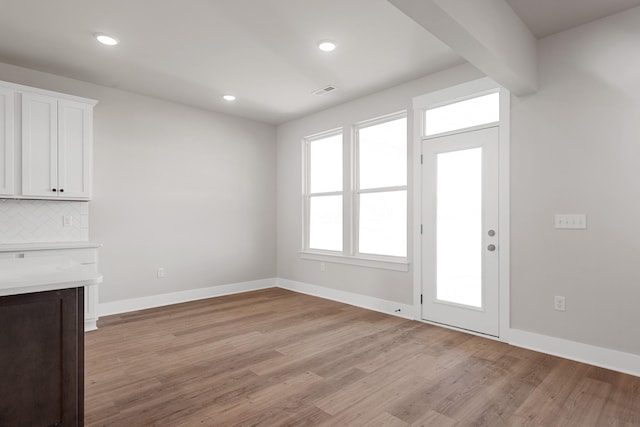 unfurnished living room featuring baseboards, light wood-type flooring, visible vents, and recessed lighting