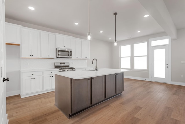 kitchen with white cabinetry, a sink, stainless steel appliances, light countertops, and backsplash