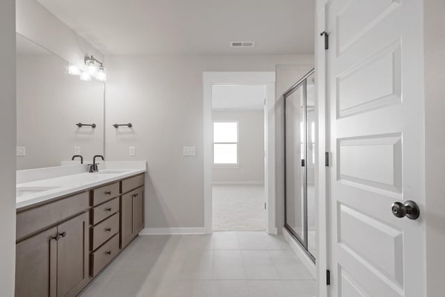 bathroom with tile patterned floors, a sink, baseboards, visible vents, and a stall shower