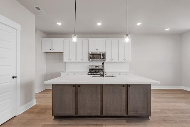 kitchen with a sink, stainless steel appliances, baseboards, white cabinetry, and light countertops