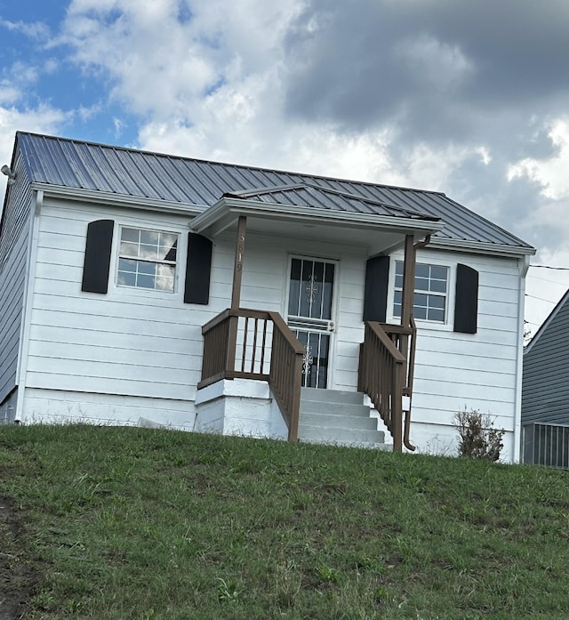 view of front of home with metal roof and a front lawn