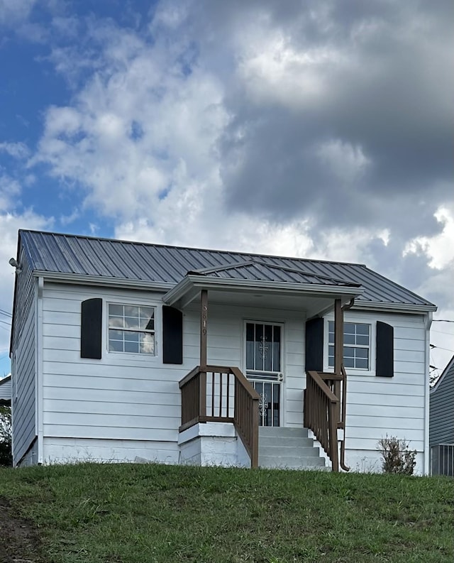 ranch-style house with a front yard and metal roof
