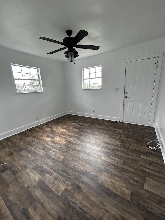 empty room featuring dark wood-style flooring, ceiling fan, and baseboards