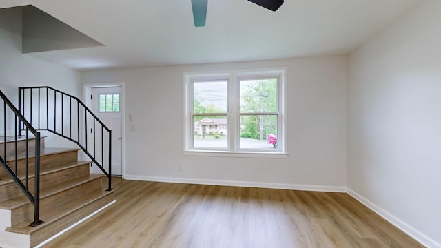 foyer featuring baseboards, stairway, wood finished floors, and ceiling fan