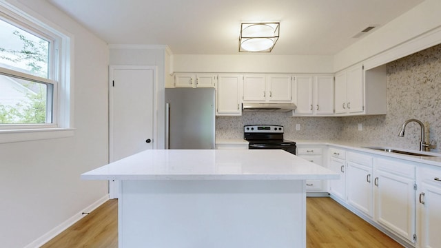 kitchen featuring a sink, under cabinet range hood, light wood-type flooring, freestanding refrigerator, and electric range