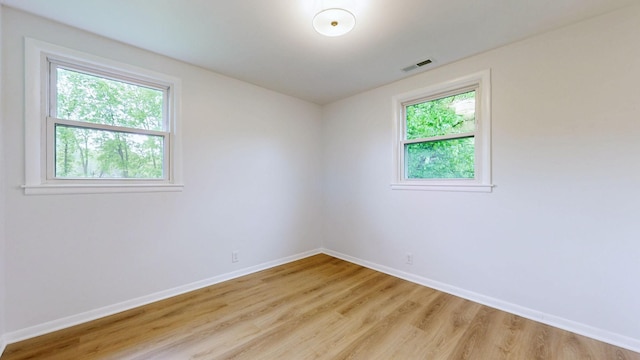 empty room featuring visible vents, light wood-style flooring, and baseboards