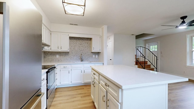 kitchen with a sink, decorative backsplash, stainless steel appliances, light wood-type flooring, and visible vents