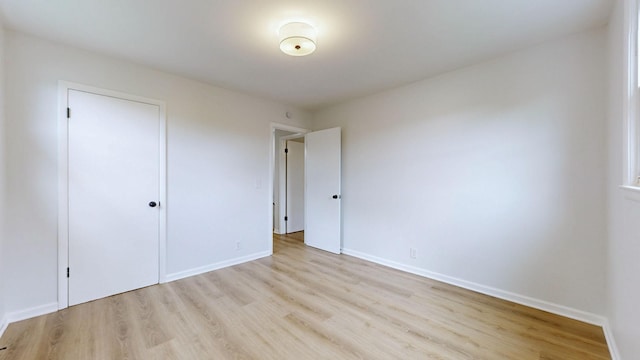 unfurnished bedroom featuring a closet, light wood finished floors, and baseboards