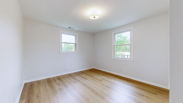 empty room featuring baseboards, light wood-type flooring, and visible vents