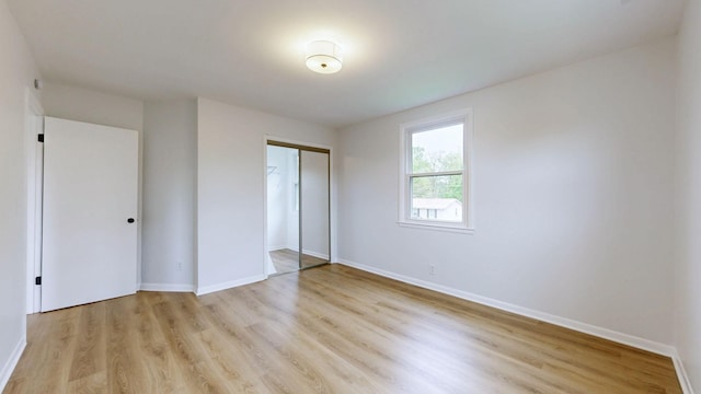 unfurnished bedroom featuring light wood finished floors, a closet, and baseboards