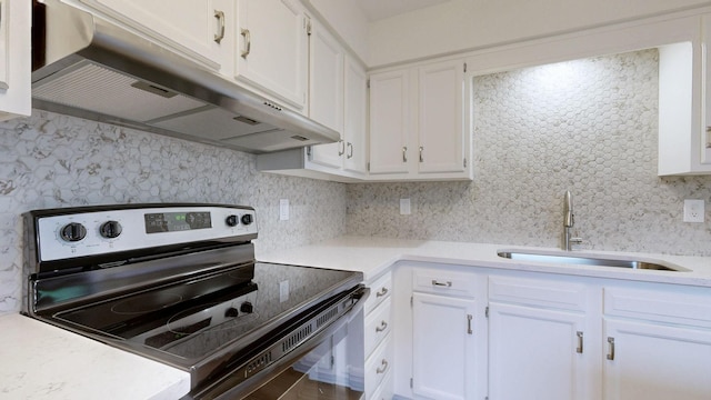 kitchen featuring electric range, under cabinet range hood, light countertops, and a sink