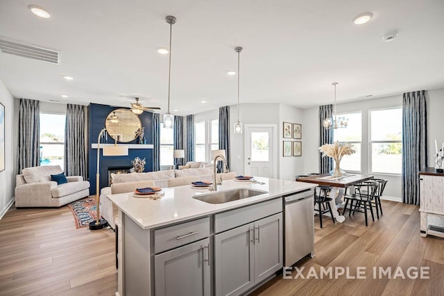 kitchen with stainless steel dishwasher, light wood-style flooring, a sink, visible vents, and gray cabinetry