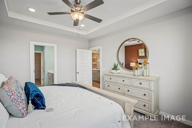 bedroom featuring a tray ceiling, baseboards, recessed lighting, a ceiling fan, and ensuite bath