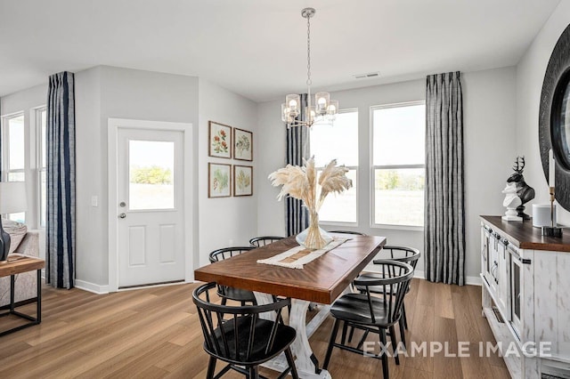 dining area with an inviting chandelier, visible vents, light wood-type flooring, and baseboards