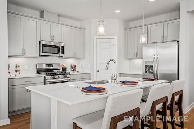 kitchen with appliances with stainless steel finishes, dark wood-style flooring, gray cabinets, and a sink