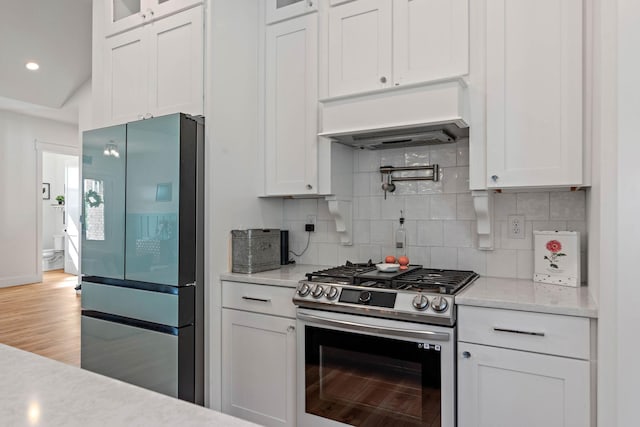 kitchen with decorative backsplash, appliances with stainless steel finishes, white cabinets, and glass insert cabinets