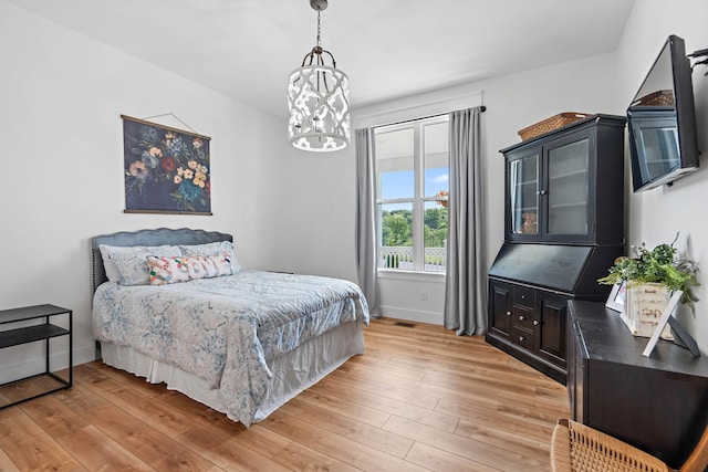 bedroom featuring light wood-style floors, baseboards, visible vents, and a chandelier