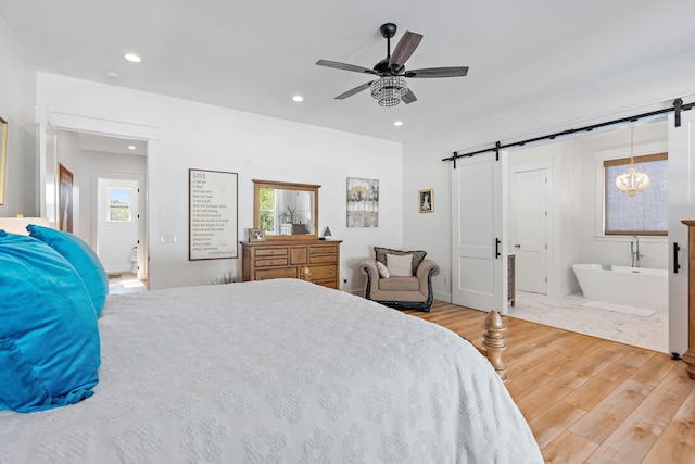 bedroom with recessed lighting, a ceiling fan, a barn door, and wood finished floors