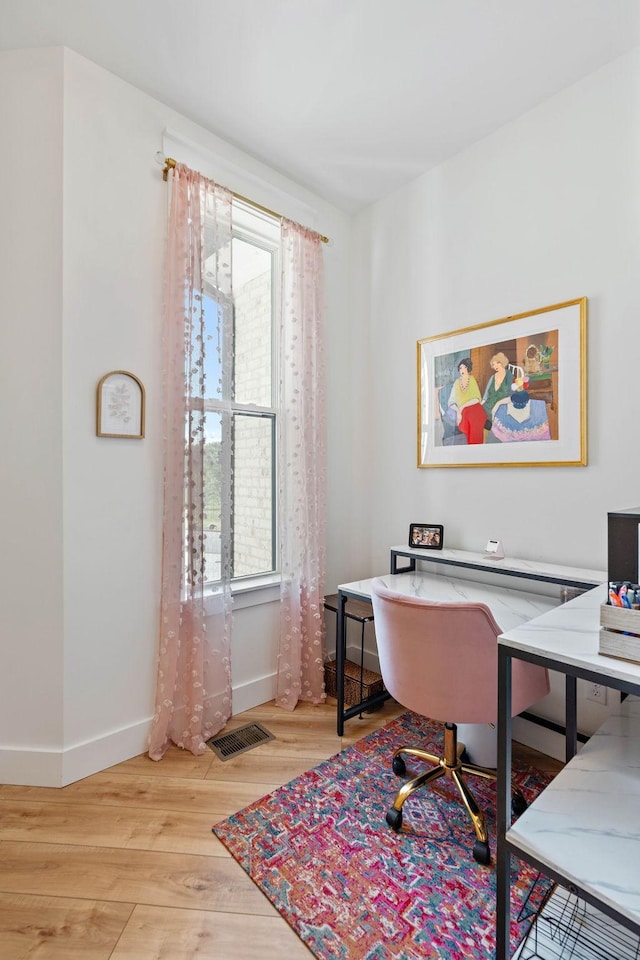 office space with visible vents, baseboards, wood finished floors, and a healthy amount of sunlight