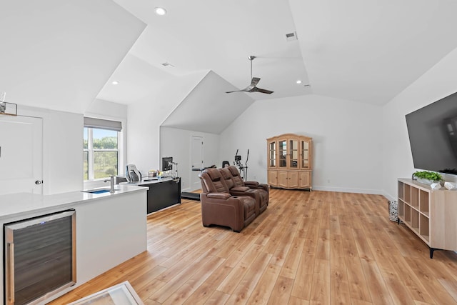 living area with visible vents, lofted ceiling, beverage cooler, light wood-style floors, and ceiling fan