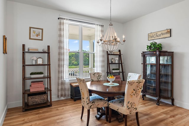 dining area with an inviting chandelier, baseboards, and light wood-style floors