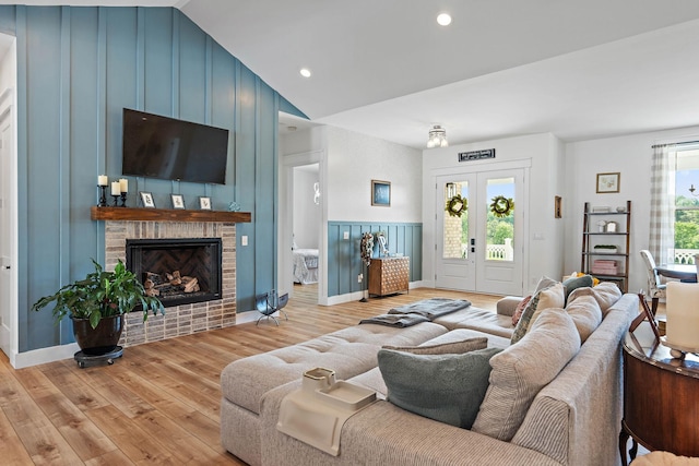 living room featuring a brick fireplace, recessed lighting, vaulted ceiling, and light wood finished floors