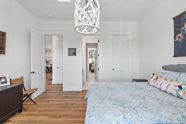bedroom featuring a closet, light wood finished floors, and a chandelier