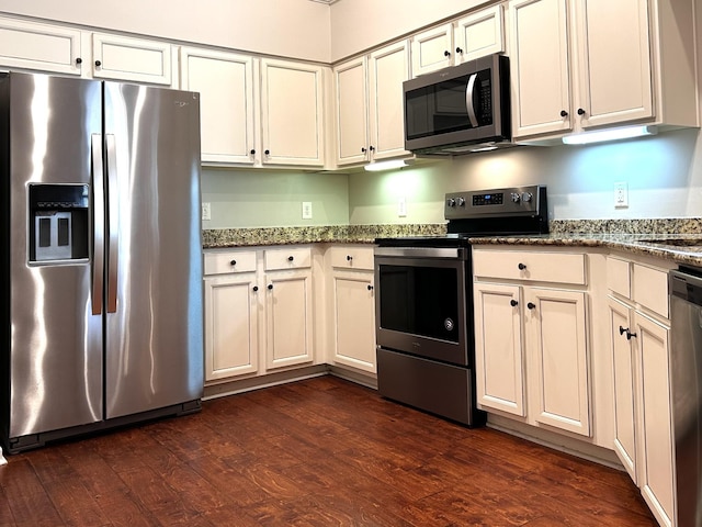 kitchen with appliances with stainless steel finishes, dark wood-type flooring, white cabinetry, and stone counters