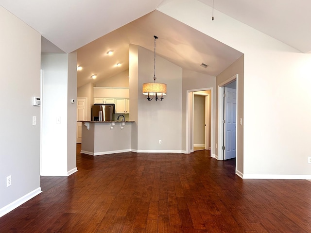 unfurnished living room featuring lofted ceiling, a sink, baseboards, an inviting chandelier, and dark wood finished floors