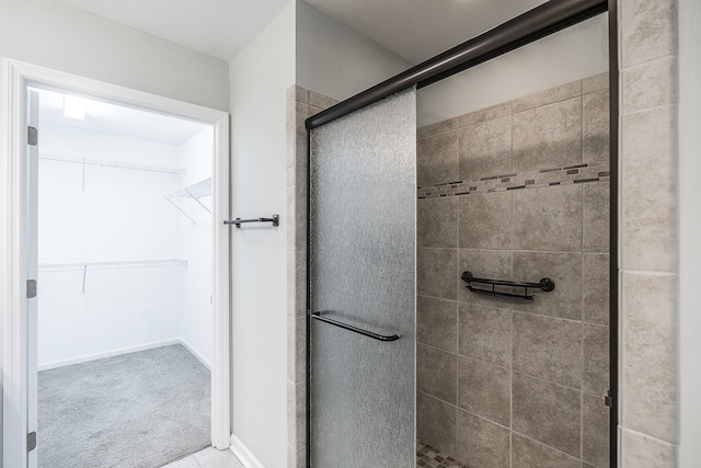 full bathroom featuring a walk in closet, baseboards, and a shower stall